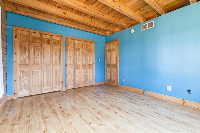 unfurnished bedroom with beamed ceiling, wood ceiling, visible vents, and multiple closets