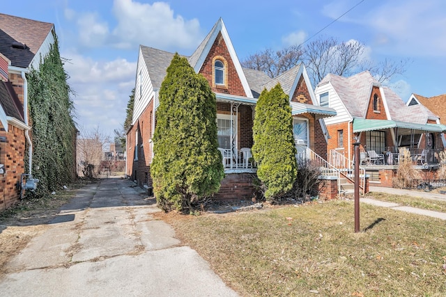 view of front of property featuring brick siding, a porch, concrete driveway, and a front lawn