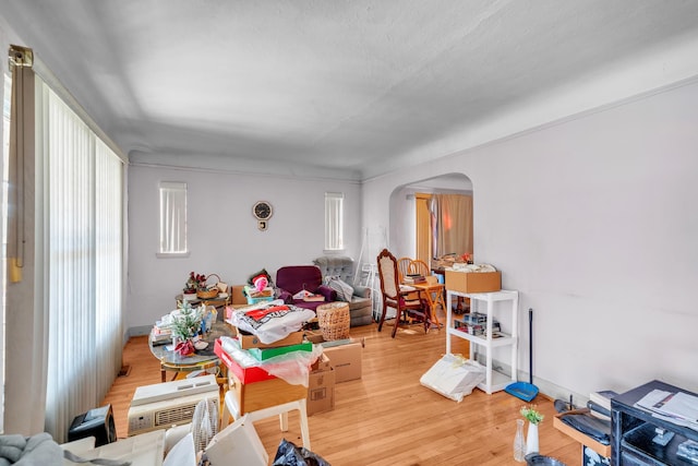 living room featuring arched walkways, baseboards, and wood finished floors
