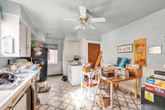 kitchen featuring a wainscoted wall, light floors, white gas range oven, and a ceiling fan