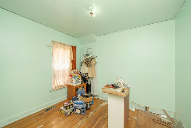 misc room with hardwood / wood-style floors, visible vents, and baseboards