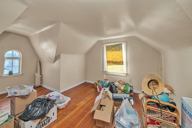 additional living space with hardwood / wood-style flooring, baseboards, and vaulted ceiling
