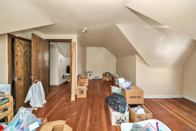 additional living space with lofted ceiling, wood finished floors, visible vents, and baseboards