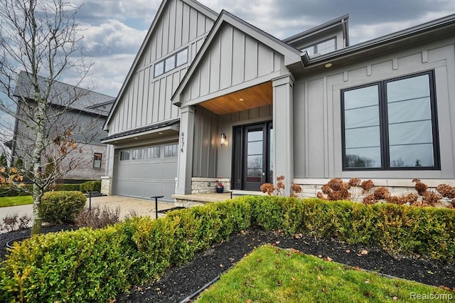 view of front of home with an attached garage, board and batten siding, and stone siding