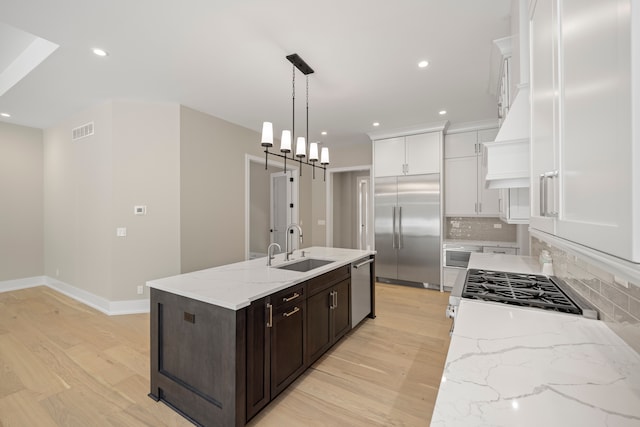 kitchen with visible vents, light wood-type flooring, stainless steel appliances, white cabinetry, and a sink