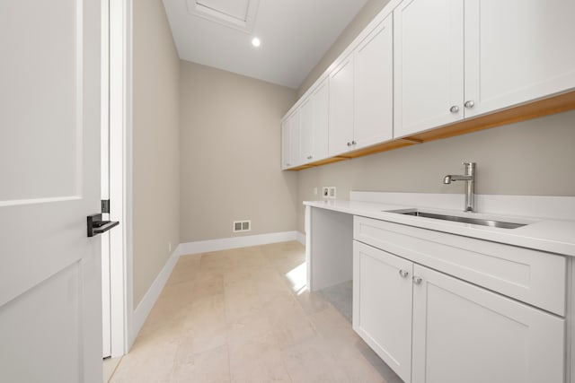 clothes washing area featuring visible vents, cabinet space, baseboards, and a sink