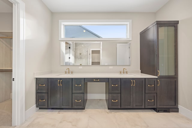 full bath featuring a sink, baseboards, a shower with door, and double vanity