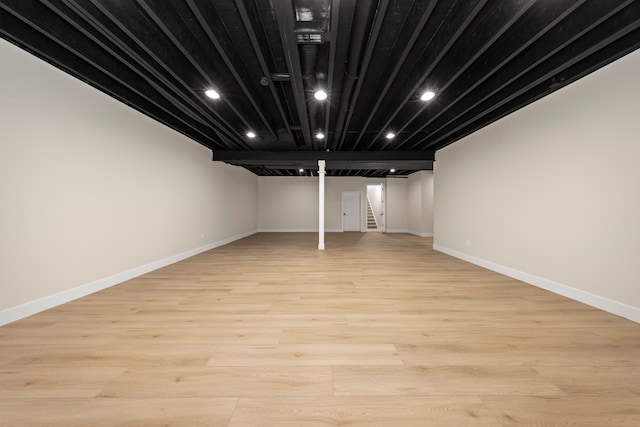 finished basement with recessed lighting, stairway, light wood-style flooring, and baseboards