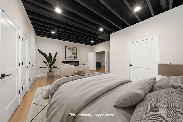 bedroom featuring beam ceiling, recessed lighting, baseboards, and light wood finished floors