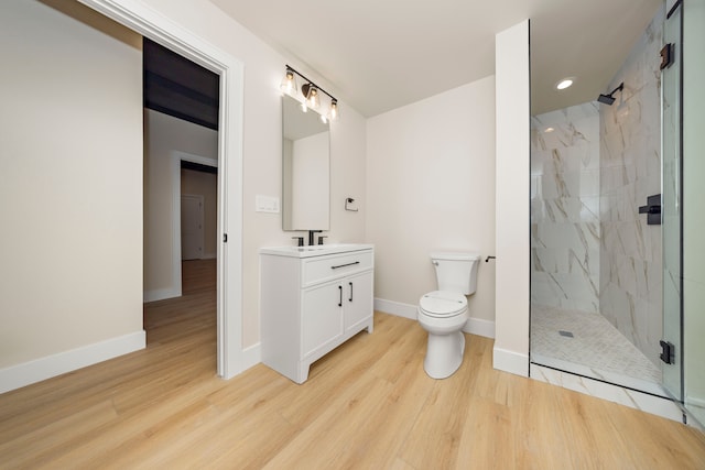 full bath with vanity, wood finished floors, baseboards, a marble finish shower, and toilet