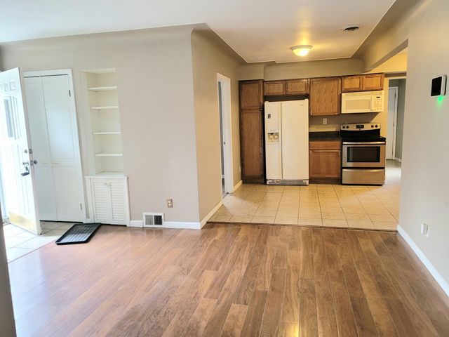 kitchen featuring white appliances, light wood-style flooring, brown cabinetry, and baseboards