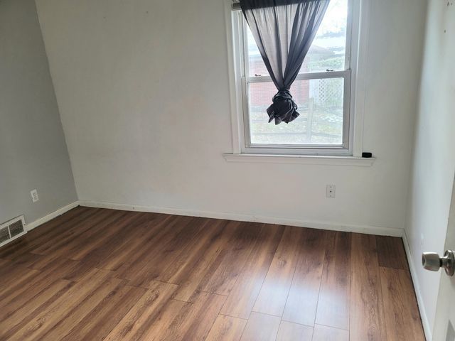 unfurnished room with visible vents, baseboards, and wood finished floors