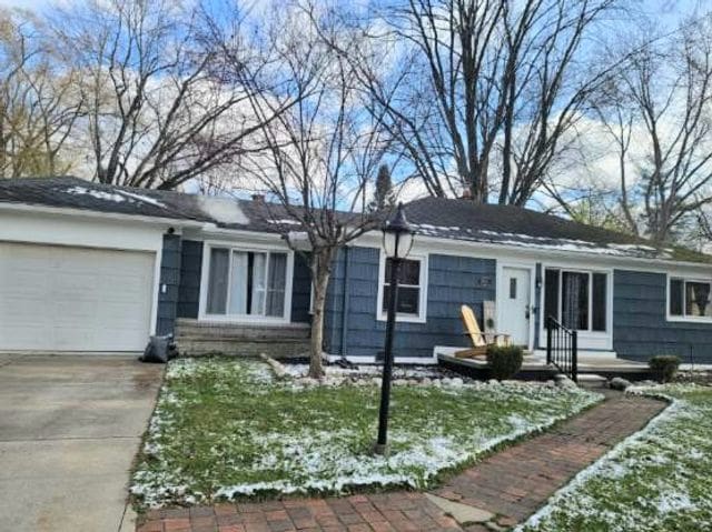ranch-style home with a front lawn, an attached garage, and driveway