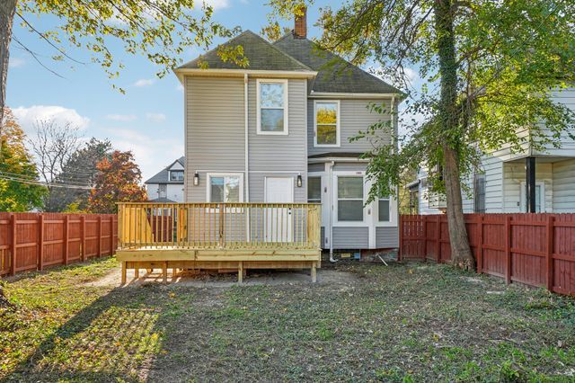3736 Iroquois St, Detroit, MI 48214 - rear view of property with a deck, a fenced backyard, and a chimney