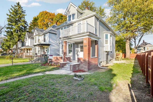3736 Iroquois St, Detroit, MI 48214 - traditional style home with brick siding, a porch, a front yard, a fenced backyard, and a balcony