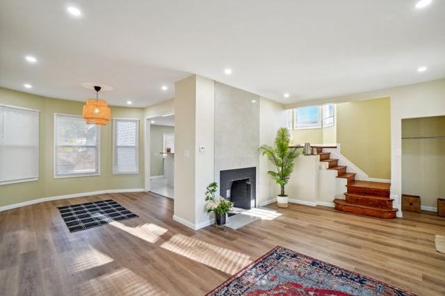 3736 Iroquois St, Detroit, MI 48214 - unfurnished living room featuring a large fireplace, baseboards, stairs, recessed lighting, and wood finished floors
