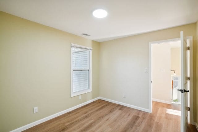 3736 Iroquois St, Detroit, MI 48214 - empty room featuring visible vents, light wood-style flooring, and baseboards