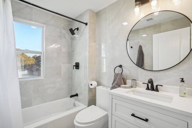 3736 Iroquois St, Detroit, MI 48214 - bathroom featuring backsplash, tub / shower combination, toilet, vanity, and tile walls