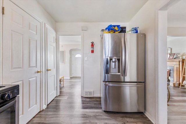 kitchen with electric range, visible vents, wood finished floors, stainless steel fridge, and baseboards