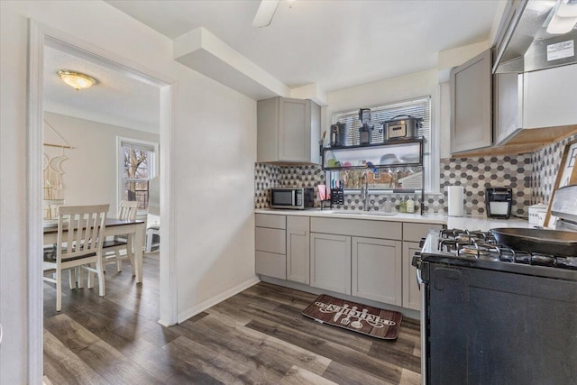 kitchen with dark wood-style flooring, gray cabinets, a sink, decorative backsplash, and appliances with stainless steel finishes