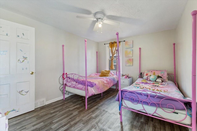 bedroom featuring wood finished floors, baseboards, visible vents, ceiling fan, and a textured ceiling