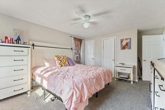 bedroom featuring two closets, a textured ceiling, carpet, and a ceiling fan