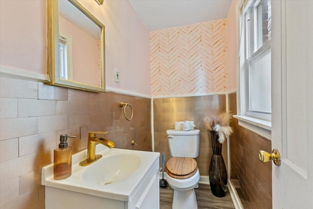 half bathroom with tile walls, toilet, and plenty of natural light