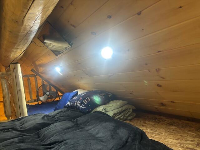 bedroom with lofted ceiling and wood walls