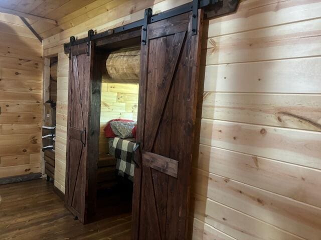 interior space featuring a barn door, wood-type flooring, and wood walls