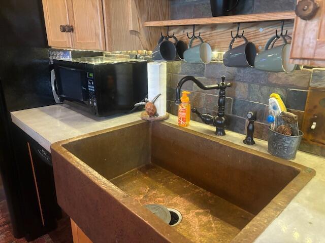 room details featuring tasteful backsplash, black microwave, and a sink
