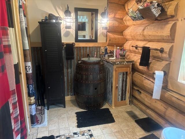 bathroom with rustic walls, visible vents, wainscoting, and vanity