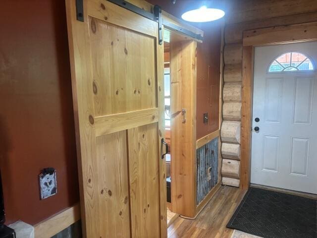 entryway featuring rustic walls, a barn door, and wood finished floors