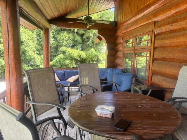 wooden terrace with outdoor dining area and a ceiling fan