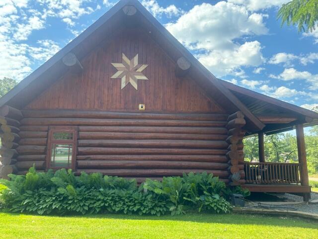 view of property exterior with log siding, covered porch, and a yard