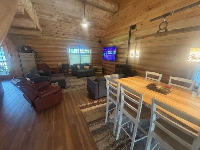 dining space featuring high vaulted ceiling, wood finished floors, and rustic walls