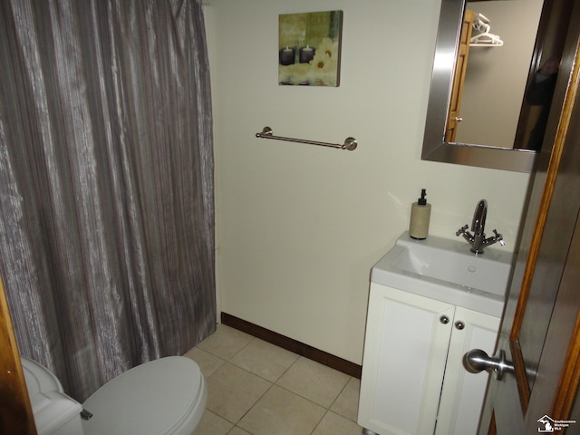 bathroom featuring vanity, baseboards, tile patterned floors, and toilet