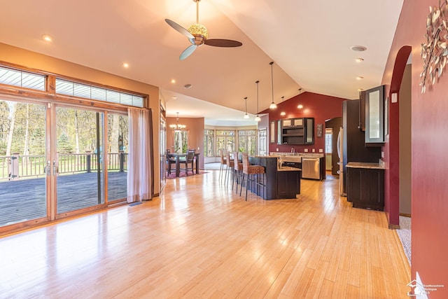 interior space featuring arched walkways, ceiling fan with notable chandelier, recessed lighting, light wood-type flooring, and vaulted ceiling