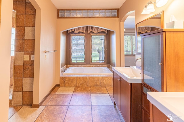 bathroom featuring a garden tub, tiled shower, and two vanities