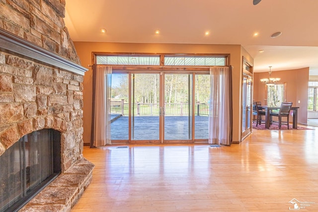 living room featuring recessed lighting, a fireplace, light wood-type flooring, and a chandelier
