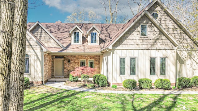 view of front facade featuring a shingled roof, board and batten siding, and a front yard
