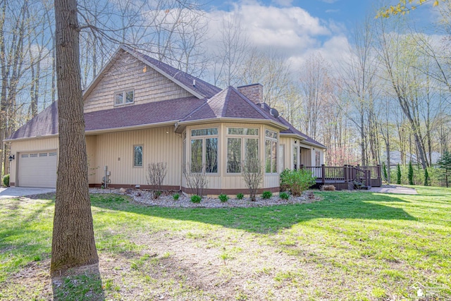 view of home's exterior featuring roof with shingles, a garage, a wooden deck, a yard, and driveway