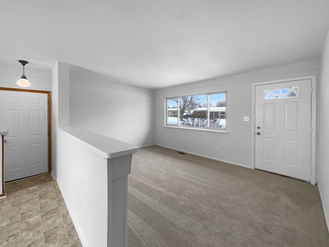 foyer entrance with light carpet and baseboards