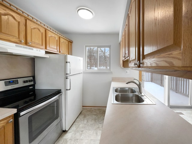 kitchen with a sink, light countertops, stainless steel range with electric cooktop, and under cabinet range hood