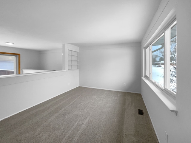 spare room featuring baseboards, visible vents, and carpet floors