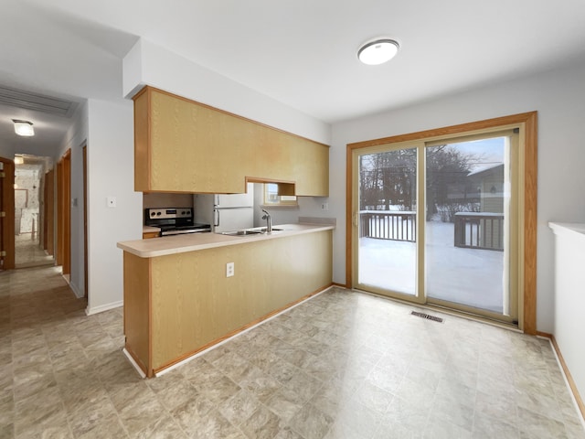 kitchen with light countertops, visible vents, a sink, a peninsula, and electric range