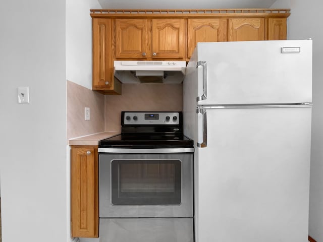 kitchen featuring brown cabinets, under cabinet range hood, stainless steel electric range, light countertops, and freestanding refrigerator