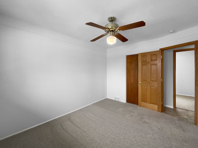 carpeted empty room featuring a ceiling fan, visible vents, and baseboards