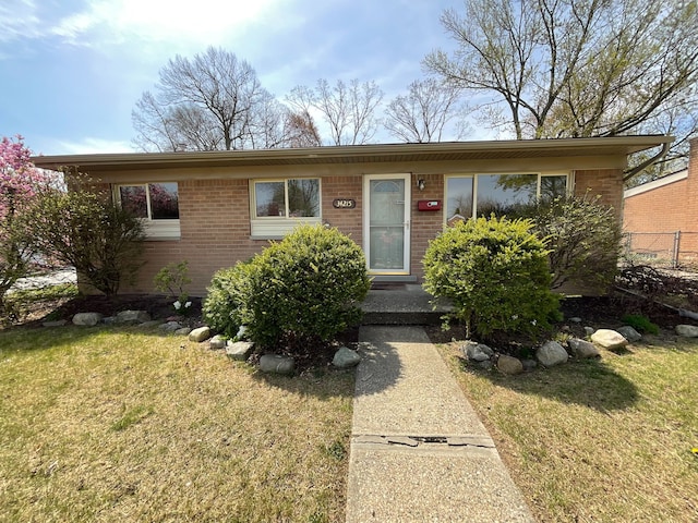 view of front of home featuring brick siding, a front lawn, and fence
