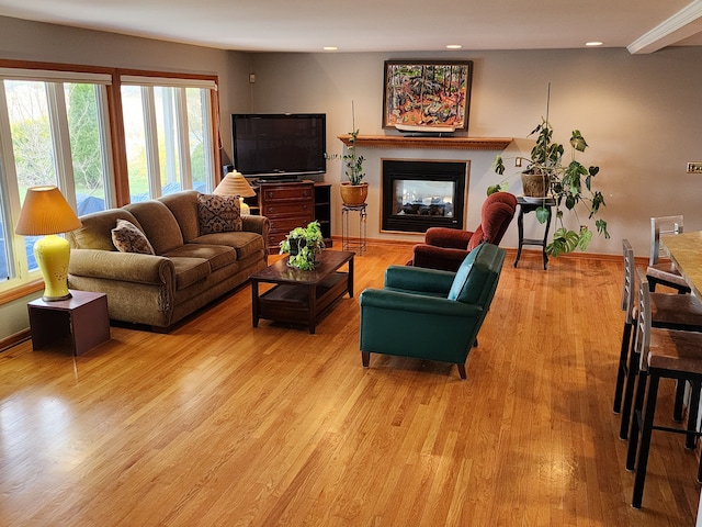 living area featuring baseboards, light wood-style floors, a glass covered fireplace, and recessed lighting