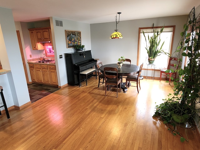 dining area featuring light wood finished floors, visible vents, and baseboards